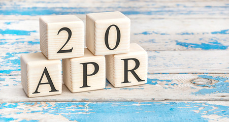 April 20th. Wooden cubes with date of 20 April  on old blue wooden background.