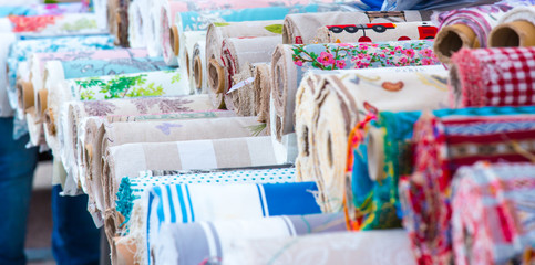 viele Rollen mit textilen Stoffen liegen auf einem Markt