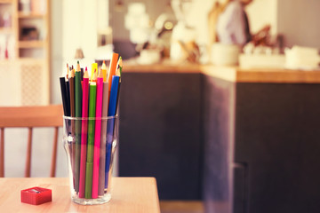 Colorful pencils in glass, toned. Cafe interior. Creative ideas concept