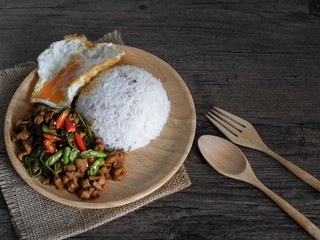 Vintage style Thai - Indian traditional food Rice topped with stir-fried chicken and basil with omelette on wooden background