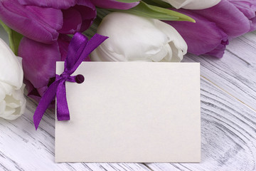 Purple and white tulips with white paper on a white wooden background. Womans Day. 8 March.