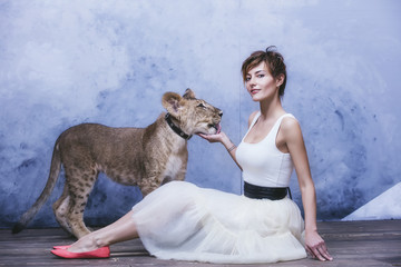 Beautiful fashionable young woman with a little alive lion cub