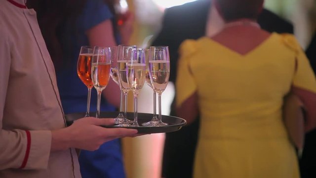 Waiter hold tray with glasses of champagne on event celebration indoors