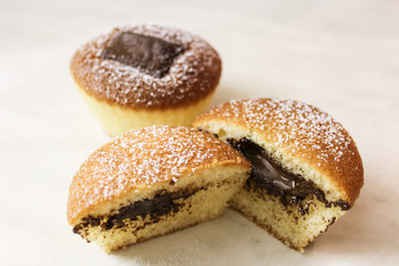 Two muffins with chocolate. One cut to half on white background