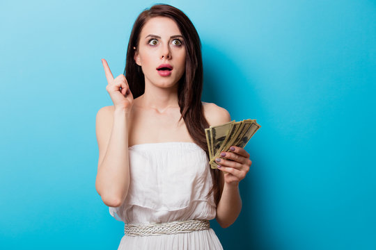 beautiful surprised young woman with money standing in front of wonderful blue background