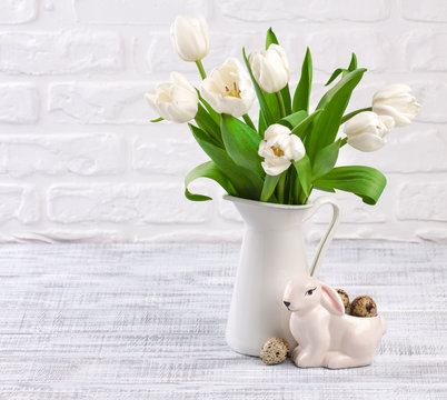 easter composition with eggs, spring tulips and porcelain easter bunny on old wooden table