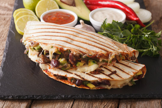 Mexican quesadilla with beef, beans, avocado and cheese close-up. horizontal