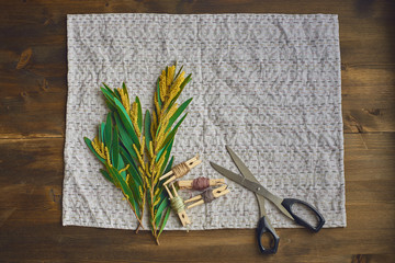three sprigs of yellow acacia, mimosa on embroidered with colored thread table napkins, tablecloths, on old brown wooden background