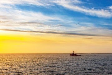 Naklejka na ściany i meble Tugboat at sunset on sea