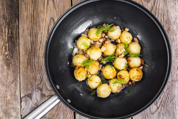 Fried potato dumplings with bacon in frying pan
