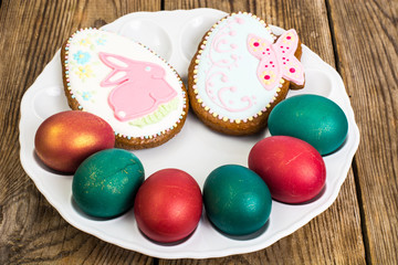 Fototapeta na wymiar Easter colored eggs and cakes with icing on white plate