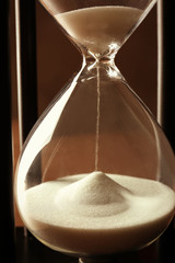 Black hourglass with white sand, closeup