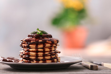 Plate with delicious pancakes on wooden table