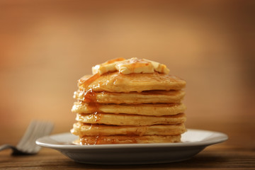 Plate with delicious pancakes on wooden table