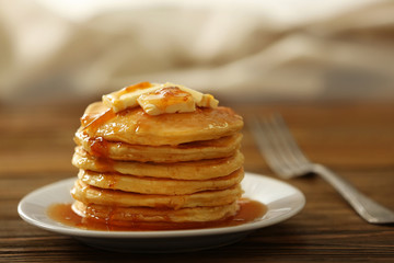 Plate with delicious pancakes on wooden table