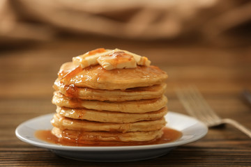 Plate with delicious pancakes on wooden table