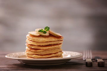 Plate with delicious pancakes on wooden table