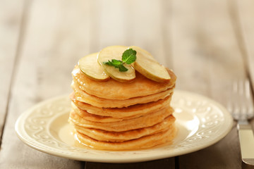 Plate with delicious pancakes on wooden table