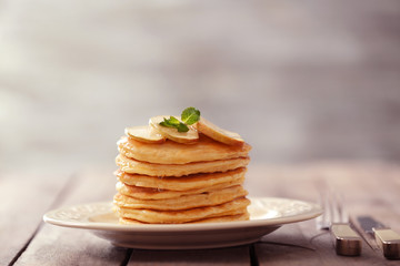 Plate with delicious pancakes on wooden table