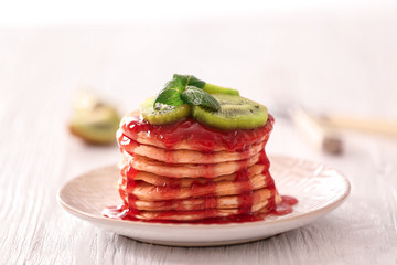 Plate with delicious pancakes on wooden table