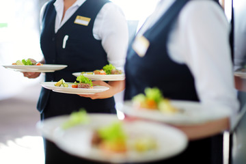 Waiter carrying plates with meat dish on some festive event