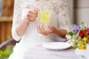 Fototapeta na wymiar Woman in white dress drinking hot ginger tea