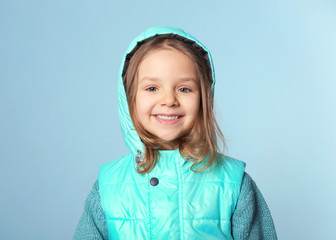 Cute little girl in warm clothes on color background