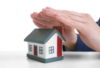 Female hands under small model of house on table, closeup