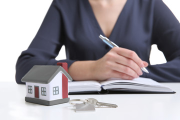 Model of house with key and woman on background