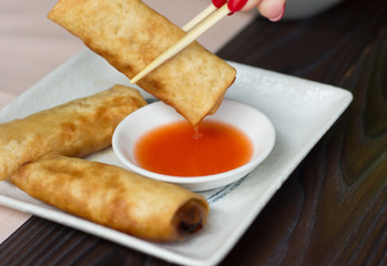 Woman hand taking spring roll with a chopstick