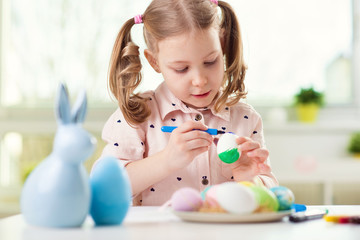 Happy pretty child girl having fun during painting eggs for easter in spring