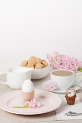 Fototapeta na wymiar Handmade Natural Linen Napkin With Handmade Cross Stitching. Hyacinth Flowers. Amaretti Biscuits. Boiled Egg. Cup Of Tea