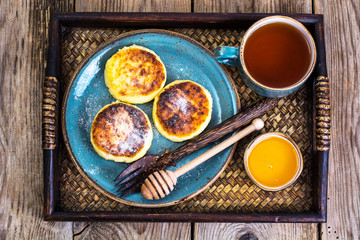 Pancakes with honey on vintage bowl on wooden tray