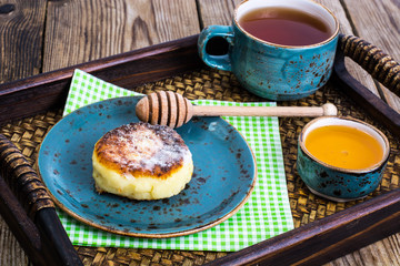 Pancakes with honey on vintage bowl on wooden tray