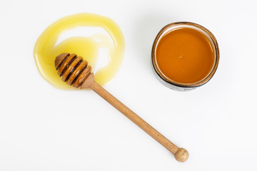 Freshly fragrant honey into a bowl and dipper on white backgroun