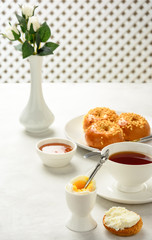 Delicious and healthy breakfast of granola, buns brioche, honey and black tea on a light background. Soft fokus.