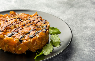 Delicious the tartare sauce from a salmon , rich in omega 3 oil, with aromatic herbs and spices with a lemon, on black background. Healthy and diet food.