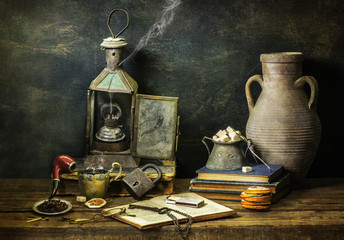 Classic still life with vintage books placed with old lamp,pipe,cup of coffee,dry oranges,tobacco, sugar and old jar on rustic wooden background. © dinasaeed