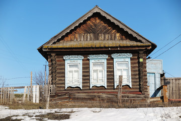 Old log house in the remote Russian village in the early spring against a blue sky