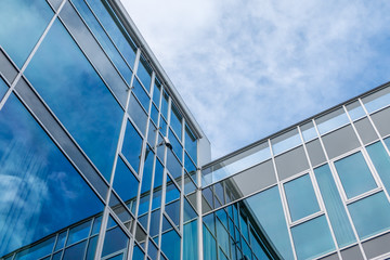 Fototapeta na wymiar Glasfront, Konzerngebäude, spiegelnde Wolken