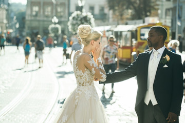 Happy african American groom and cute bride dancing on street