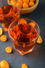 orange kumquat  liqueur in the  glasses on dark concrete table