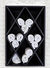 Black cabinet with white towels, which are twisted into a roll