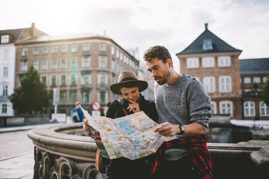 Young tourist couple exploring a city map.