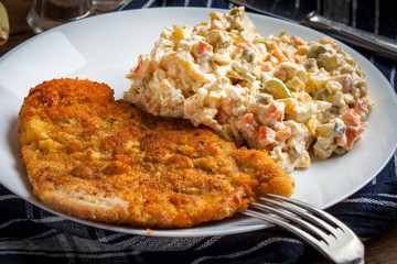 Fried pork chop in breadcrumbs, served with vegetable salad.