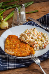 Fried pork chop in breadcrumbs, served with vegetable salad.