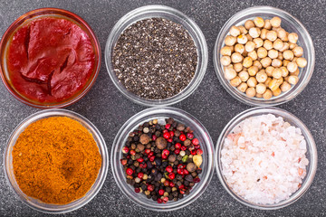 Various dry spices, sauces and cereals in glass molds on backgro