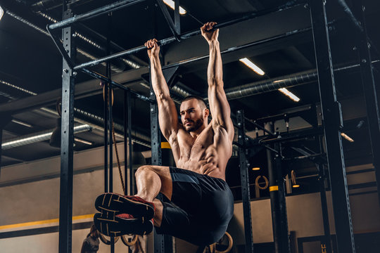 A Man Doing ABS Workouts On Pull Up Bar In A Gym Club.