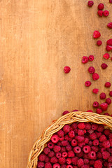 Ripe sweet wild raspberries in basket on wooden table. Close up, top view