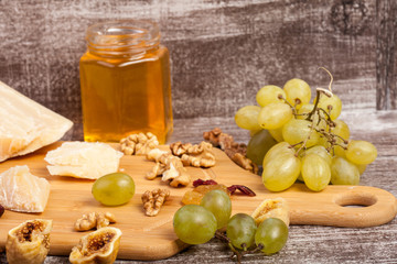 Cheese, honey and grape on wooden background